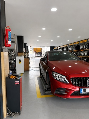 Servis alanı — kırmızı araç ve lastik raflarıyla profesyonel atölye